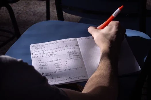 a budget android tablet on a desk playing an online lecture video, a notebook and pen beside it, warm afternoon window light, side angle close-up, editorial lifestyle photography, no face