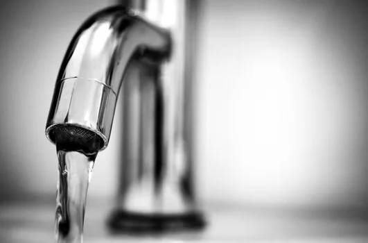 a close-up of a stainless steel bidet nozzle extended under a clean white toilet seat, water droplets, soft bathroom lighting, hygienic minimal look, editorial macro photography, no people