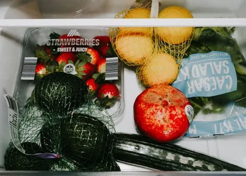 a close-up of kimchi storage containers neatly stacked inside a refrigerator drawer, dark red kimchi visible through translucent lids, bright clean interior, soft natural light, editorial lifestyle photography, no people