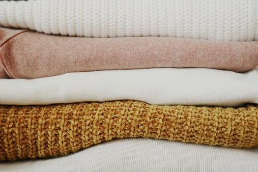 a close-up of neatly folded fluffy white towels and soft cotton clothes on top of a dryer, warm soft light, editorial lifestyle photography, shallow depth of field, no people