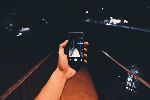 a large-screen smartphone held in one hand showing a bright AMOLED display in a cozy cafe, shallow depth of field, soft daylight, editorial photography