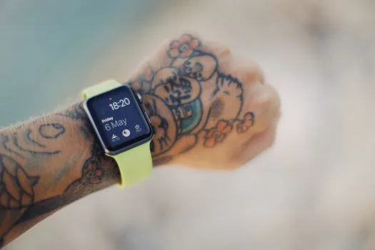 a person's wrist wearing a smartwatch while holding a smartphone, soft window light, close-up on the watch screen, editorial product photography, shallow depth of field