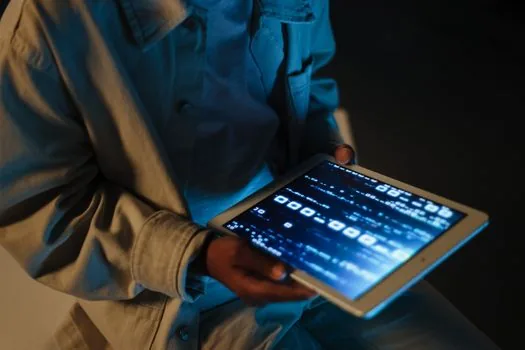 a person using a small tablet for reading an e-book while commuting, hands holding the device, blurred background, soft light, editorial lifestyle photography, no face close-up