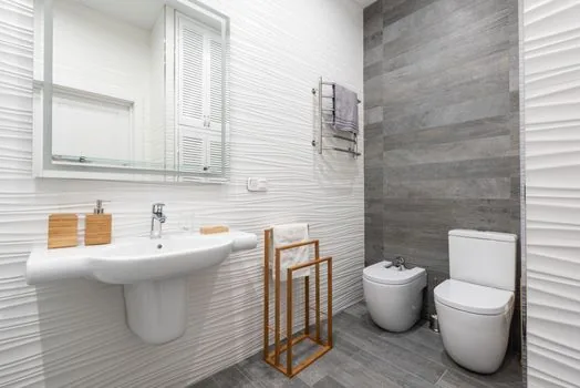 a sleek white electronic bidet seat attached to a toilet in a bright Korean apartment bathroom, control panel on the side, clean tiled wall, natural daylight, editorial interior photography, no people