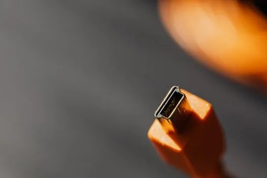 a smartphone charging from a black power bank on a wooden cafe table, a short usb-c cable connecting them, soft warm window light, close-up product shot, editorial photography, shallow depth of field, no people