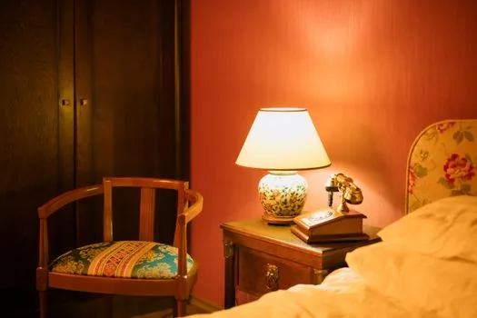 a smartwatch charging on a wireless charger beside a bed at night, warm dim lamp light, cozy bedroom mood, editorial photography, shallow depth of field