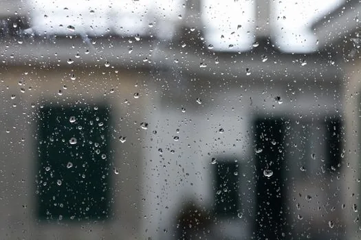 a white dehumidifier placed next to drying laundry rack in a korean apartment on a rainy day, window with raindrops, soft natural light, editorial photography