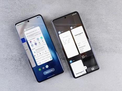 two smartphones of different sizes placed side by side on a marble tabletop for size comparison, top-down view, clean soft daylight, editorial product photography