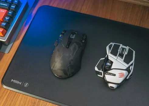 a hand resting on an ergonomic gaming mouse on a large mousepad, soft desk lighting, over-the-shoulder angle, editorial product photography, shallow depth of field