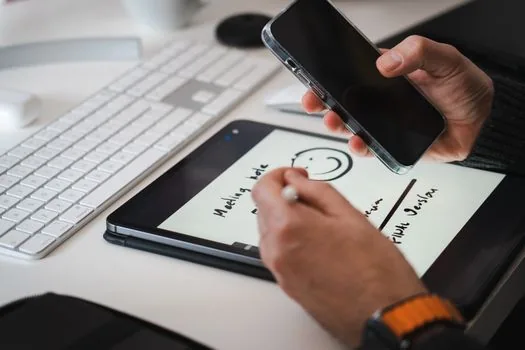 a person taking handwritten notes on a tablet with a stylus while a video lecture plays, cozy home study desk, warm afternoon light, over-the-shoulder angle, editorial photography, shallow depth of field