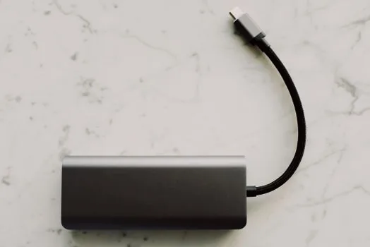 close-up of a usb-c hub showing multiple ports including hdmi and usb-a and sd card slot with cables plugged in, clean desk background, editorial product photography, shallow depth of field