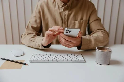 person comparing foldable phone sizes on a desk, hands only, no logo, bright neutral lighting