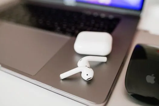 successfully connected generic wireless earbuds beside laptop showing abstract audio output icon, warm bright desk, clean finish, no logo, no readable text