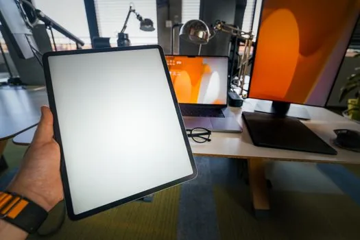three tablets of different sizes laid side by side on a neutral desk, showing size comparison, top-down editorial product photography, soft even lighting