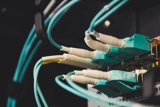 close up of video conference codec box behind meeting room display with ethernet cables and asset tag, realistic Korean office, no brand logos | 회의실 화상회의 코덱과 네트워크 케이블을 확인하는 장면