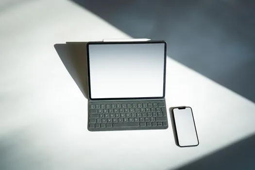 laptop and smartphone showing Google account device activity list, Korean user reviewing unfamiliar device session on clean bright desk, realistic security guide photo
