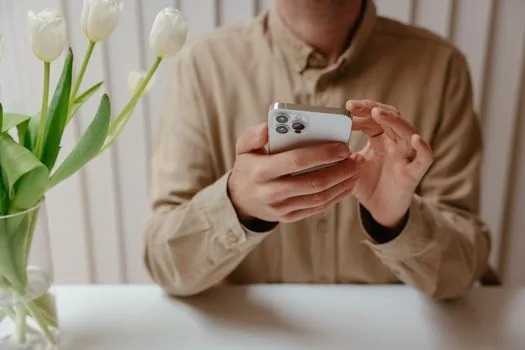 smartphone user using voice search and camera input to compare appliance manual and AI answer at desk