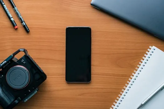 two smartphones showing migration checklist beside charging cable and notebook, realistic Korean desk photo, no brand logos