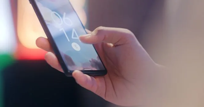 Close realistic photo of iPhone Display and Brightness Auto Lock settings in Korean, hand holding phone, clean desk, no readable personal data | 아이폰 자동 잠금 시간을 확인하는 장면