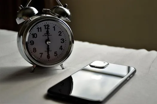 Galaxy phone asking for PIN after restart beside morning alarm clock, realistic desk scene | 자동 재시작 뒤 PIN 입력이 필요한 상황