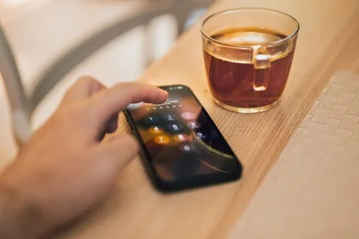 iPhone user checking verification code in filtered unknown senders folder, banking app on laptop nearby | 필터함에서 인증문자를 다시 확인하는 장면