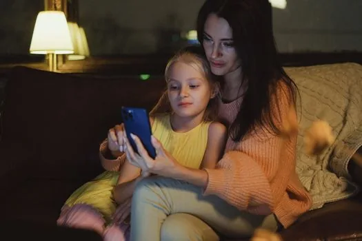 Korean parent reviewing Family Sharing Screen Time settings on iPhone beside child device on bright desk, realistic privacy-safe tutorial photo | 보호자 기기에서 자녀 스크린 타임 설정을 확인하는 장면