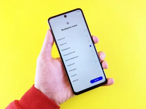 Korean user checking Android App languages settings on Samsung Galaxy phone beside bilingual notebook, realistic bright desk photo | 갤럭시 앱별 언어 설정 목록을 확인하는 장면