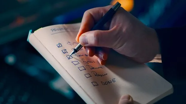 person checking AI model availability checklist on tablet beside laptop