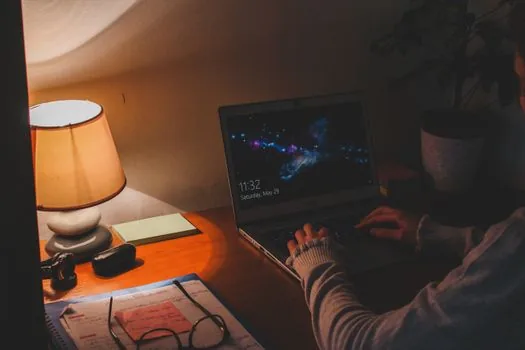 person checking scheduled night light hours on Windows 11 laptop beside wall clock, warm evening room, realistic photo | 야간 조명 예약 시간 확인 장면
