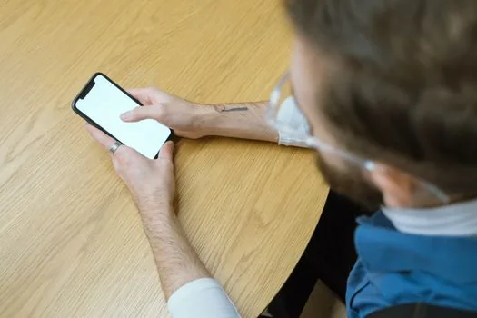 Person looking at iPhone on desk while Face ID attention aware setting concept is visible, realistic editorial photo, no text overlay | 주시 지각 기능 때문에 화면이 유지되는 상황