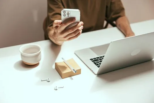 person scanning passkey QR code from laptop with smartphone, Bluetooth icon context, realistic bright desk photo, no readable account email | 패스키 QR 코드와 휴대폰 확인 장면