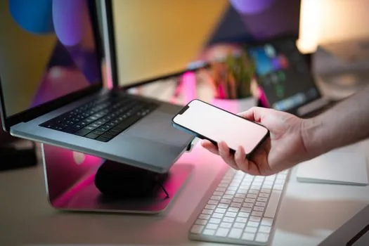 user reading Microsoft account recovery code on smartphone beside locked Windows laptop, realistic troubleshooting photo | 복구 메일 코드로 Microsoft 계정 암호를 재설정하는 장면